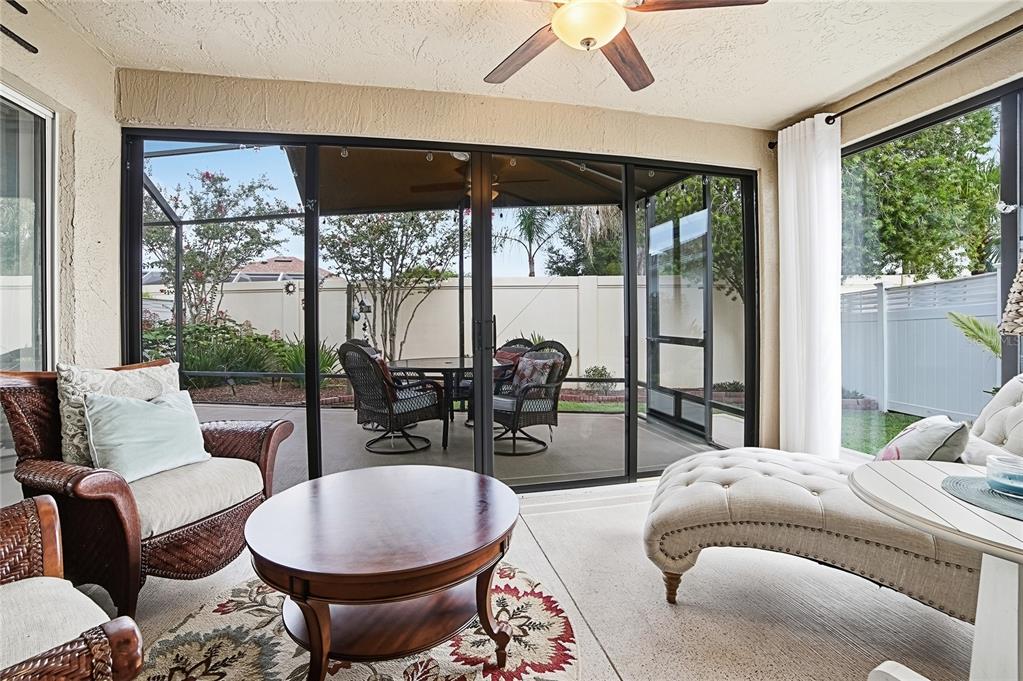 A sunroom with wicker furniture, a chaise lounge, and sliding glass doors opening to a patio — 1472 ALEXA PLACE, THE VILLAGES, FL
