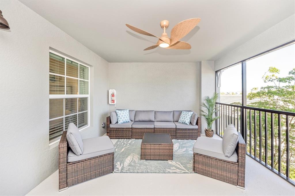 A covered balcony features wicker patio furniture, a ceiling fan, and a screened-in railing — 17500 OPAL SAND DRIVE UNIT 204, VENICE, FL