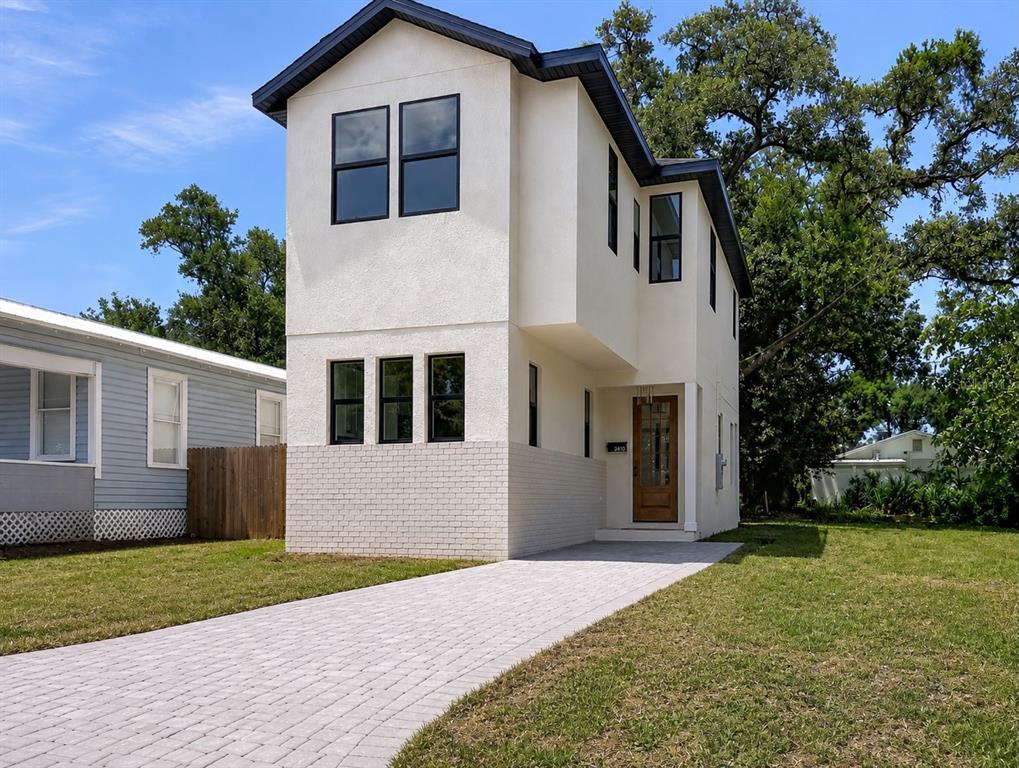 A two-story house with white stucco, a brick base, and a paved driveway — 2410 E 20TH AVENUE, TAMPA, FL