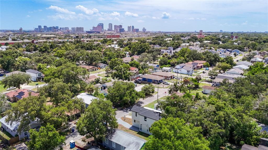 An aerial view shows a residential neighborhood with houses, trees, and a distant city skyline — 2410 E 20TH AVENUE, TAMPA, FL