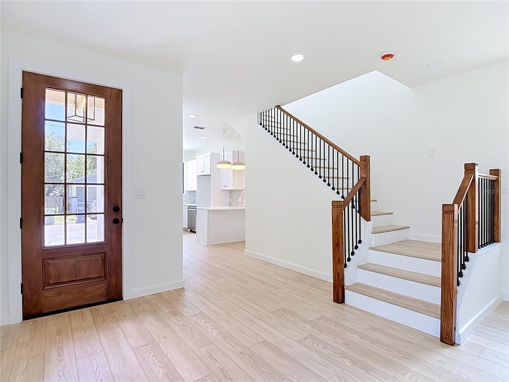 An entryway features a wood-paneled front door, light wood-look flooring, and a staircase with railings — 2410 E 20TH AVENUE, TAMPA, FL