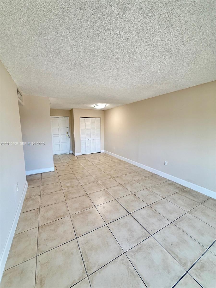 This room features beige tile flooring, light-colored walls, and a white ceiling with a light fixture — 1755 W 60th St # D312, Hialeah FL 33012, HIALEAH, FL