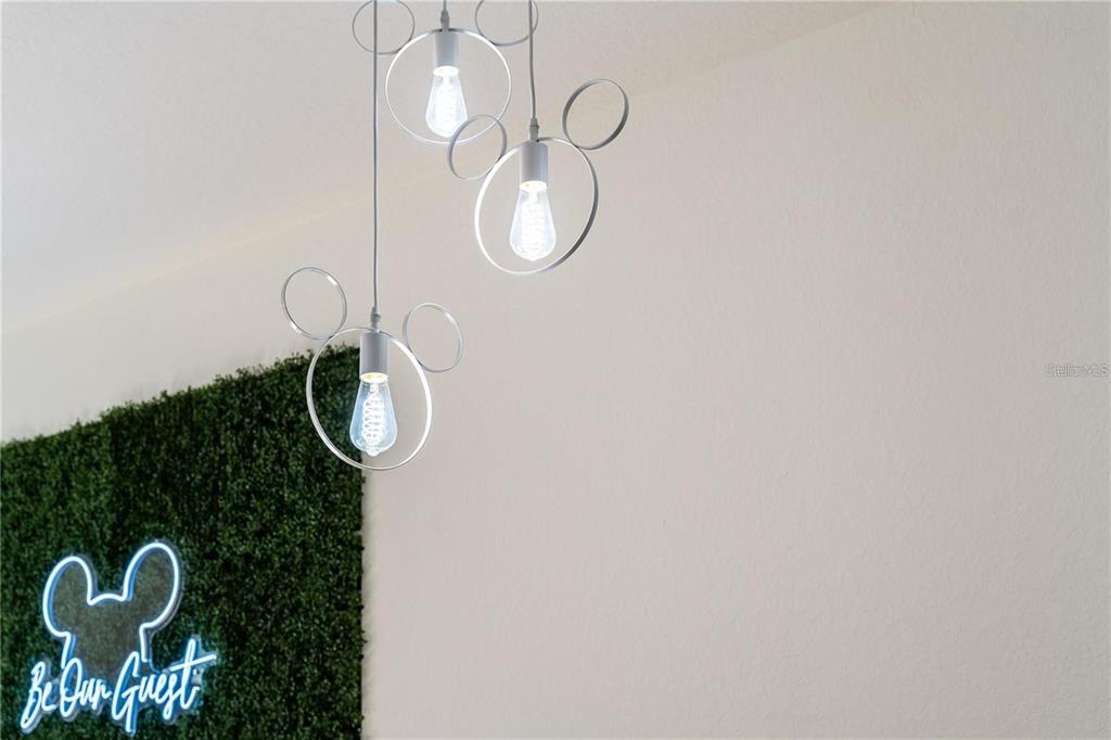 Three Mickey Mouse-shaped pendant lights hang above a green wall with a neon sign — 2622 LODI CIRCLE UNIT 103, KISSIMMEE, FL