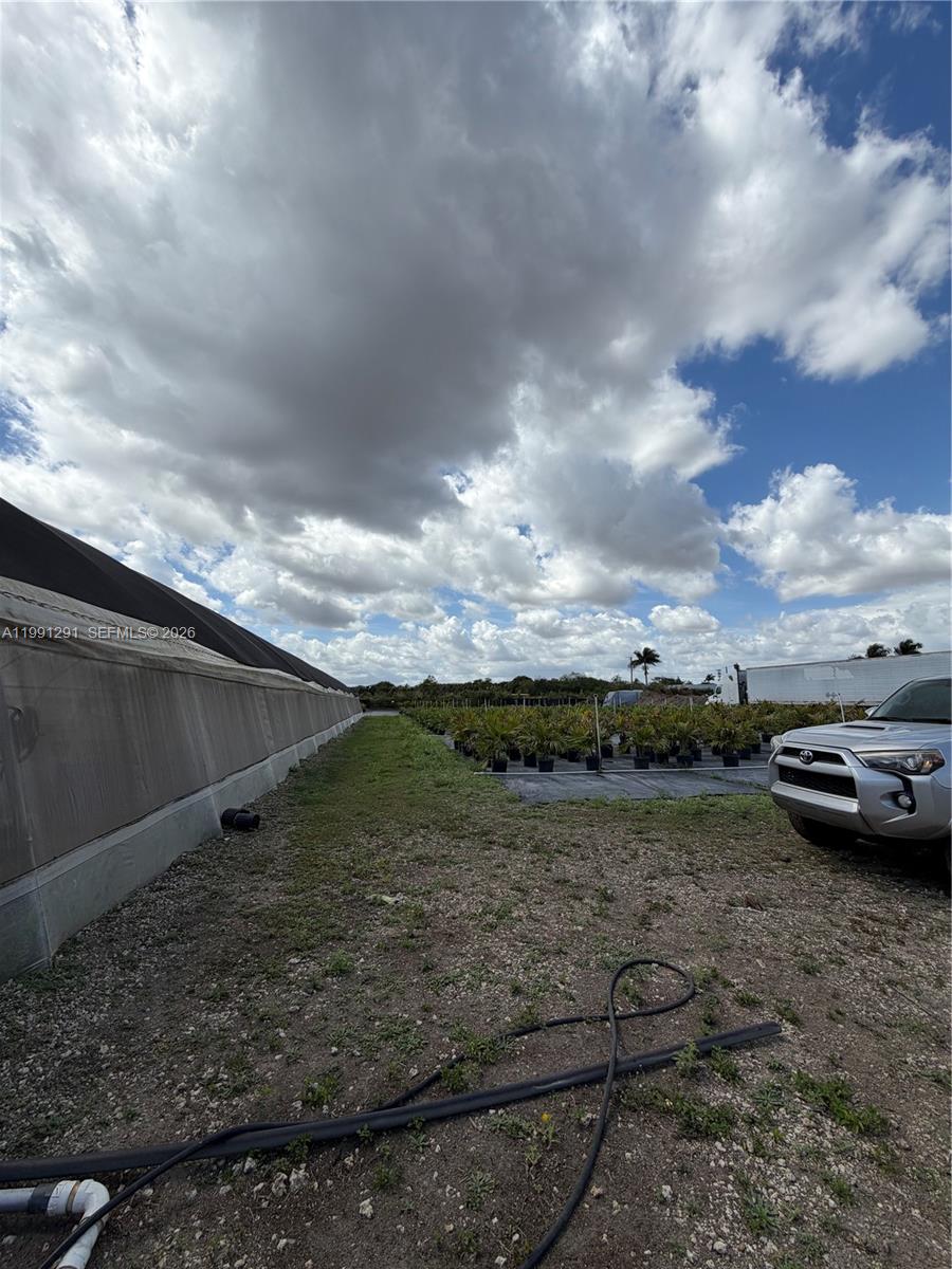 A silver SUV is parked next to a greenhouse and rows of potted plants — SW 169 Ave, Miami FL 33187, MIAMI, FL