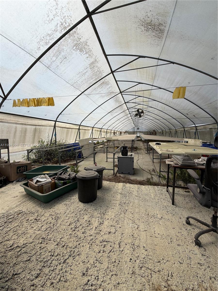 An interior view of a long greenhouse structure with metal tables and a dirt floor — SW 169 Ave, Miami FL 33187, MIAMI, FL