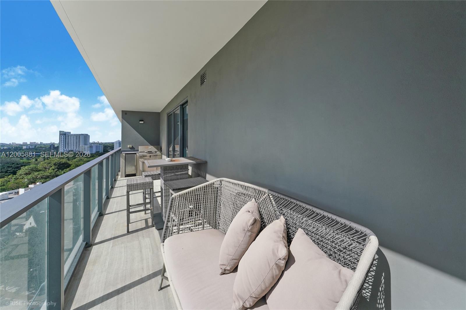 A balcony features a modern sofa, a small dining set, and an outdoor kitchen area — 1451 Brickell Ave # 1203, Miami FL 33131, MIAMI, FL