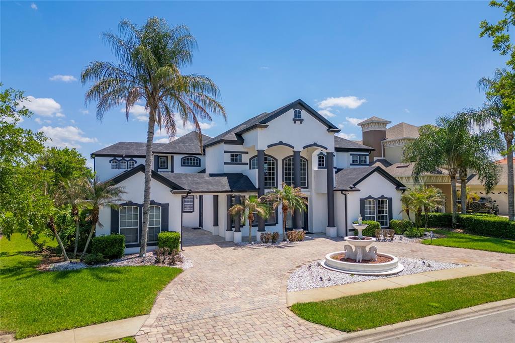 A two-story white house with a dark roof, palm trees, and a front yard fountain — 1407 WATER LILLY LANE, KISSIMMEE, FL