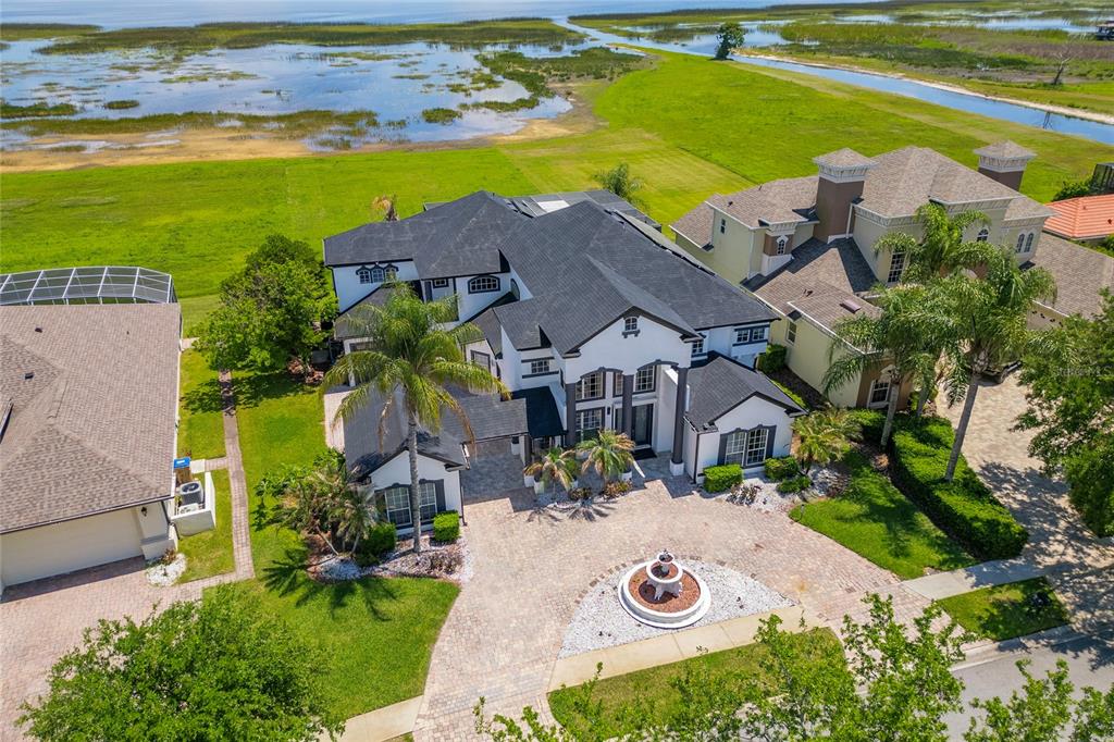 An aerial view of a large two-story house with a circular driveway and water views — 1407 WATER LILLY LANE, KISSIMMEE, FL
