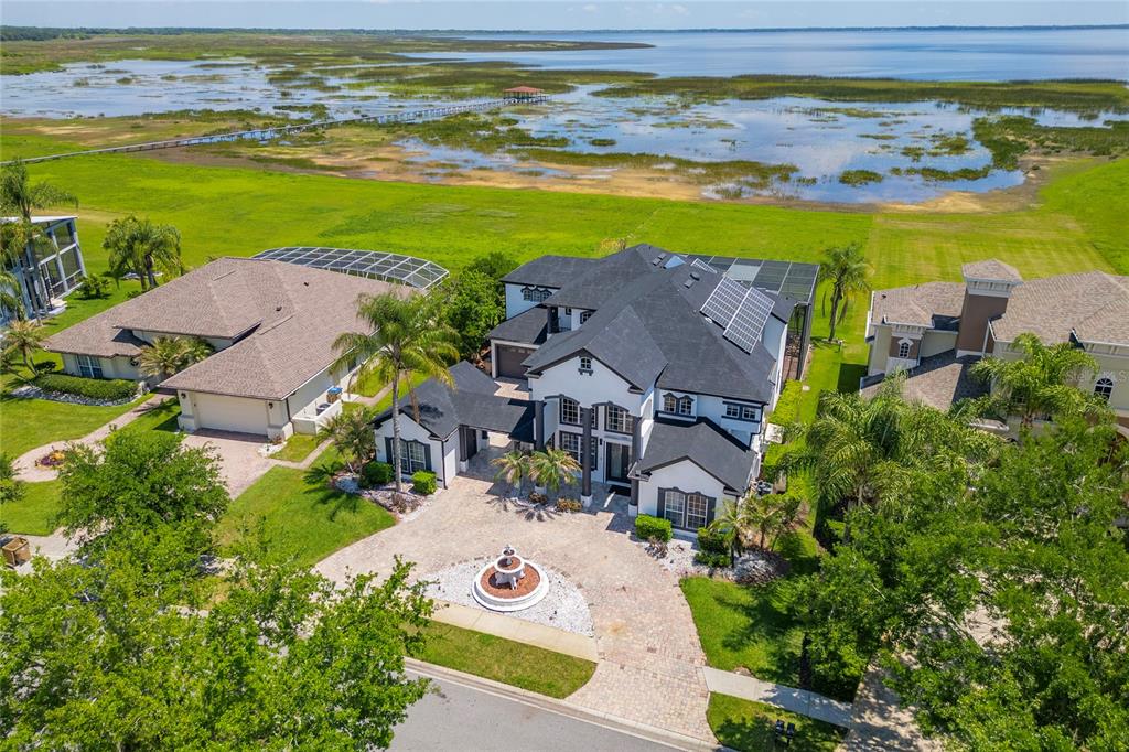 An aerial view of a large two-story house with a fountain and lakefront property — 1407 WATER LILLY LANE, KISSIMMEE, FL