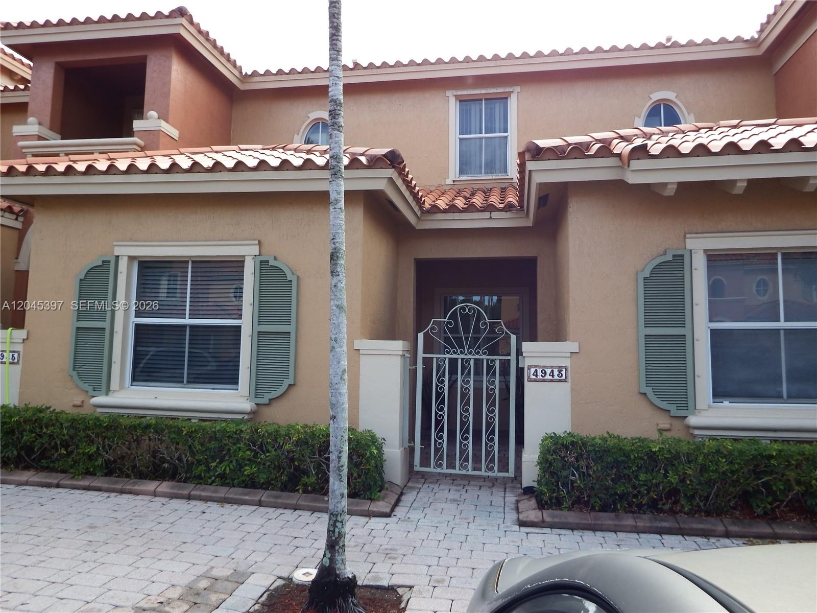 The exterior of a two-story stucco home features a gated entryway and green shutters — 4943 Leeward Ln # 3204, Dania Beach FL 33312, DANIA BEACH, FL