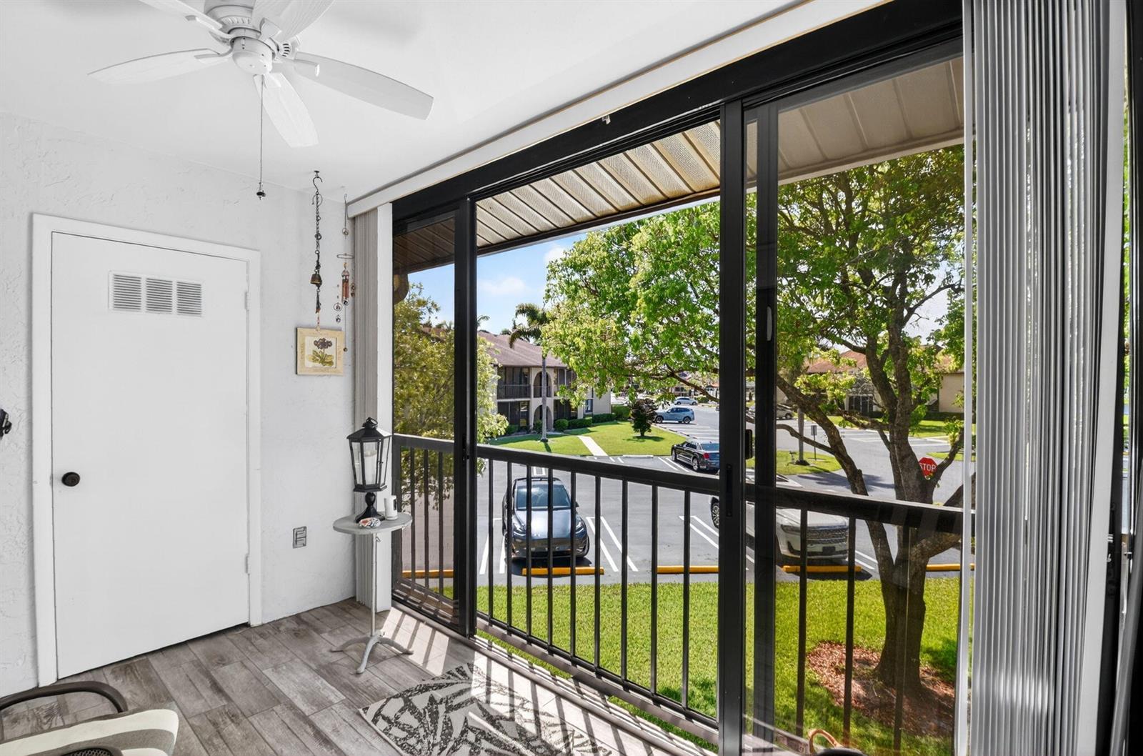 A covered balcony with wood-look tile flooring, a ceiling fan, and a view of parking — 207 Pine Hov Circle # D2, FL 33463, FL