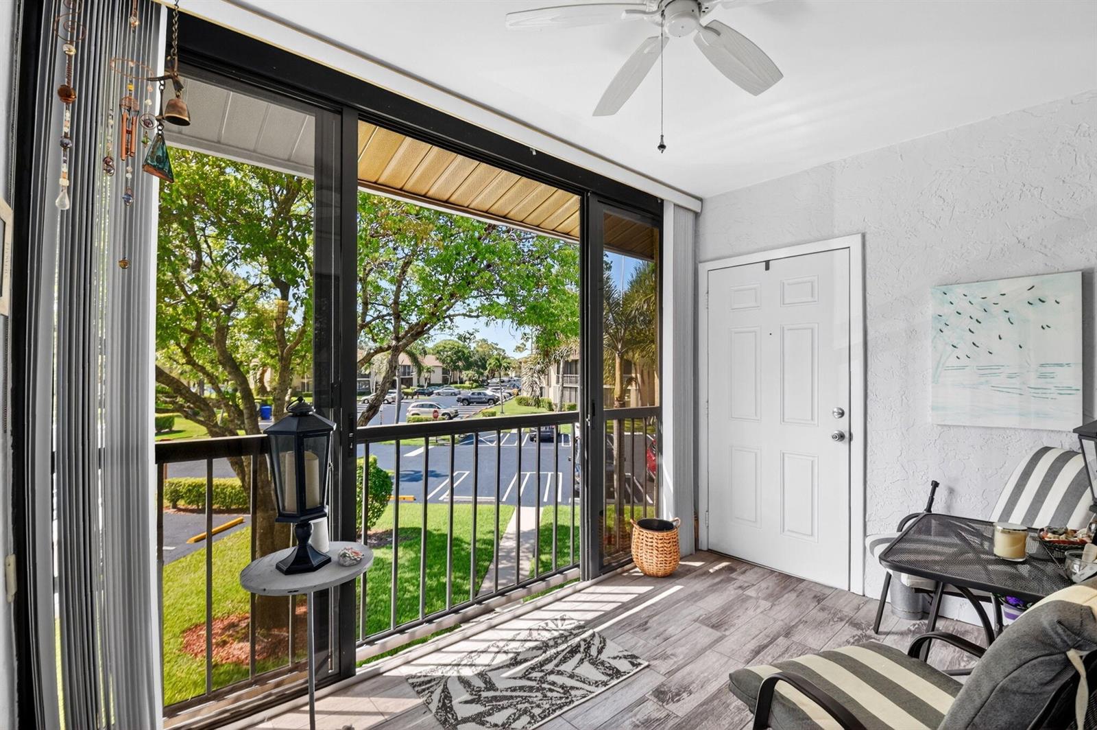 A screened-in balcony features wood-look tile flooring, a ceiling fan, and views of a parking lot — 207 Pine Hov Circle # D2, FL 33463, FL