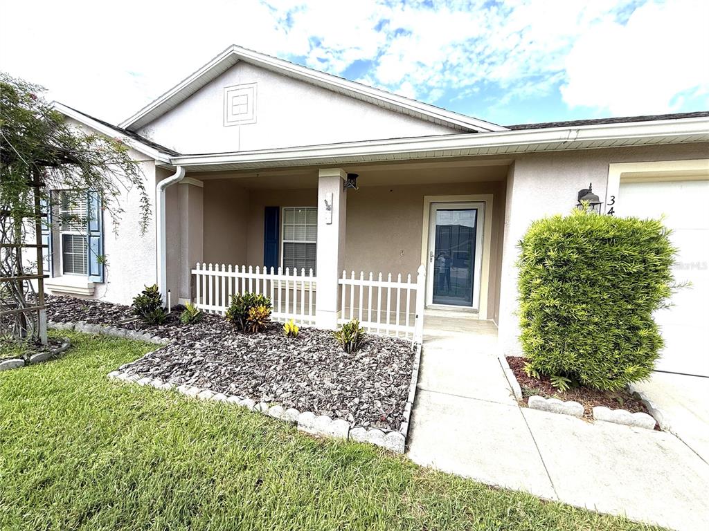 A single-story house exterior features a covered porch, a white picket fence, and landscaping — 344 SKY VALLEY STREET, CLERMONT, FL