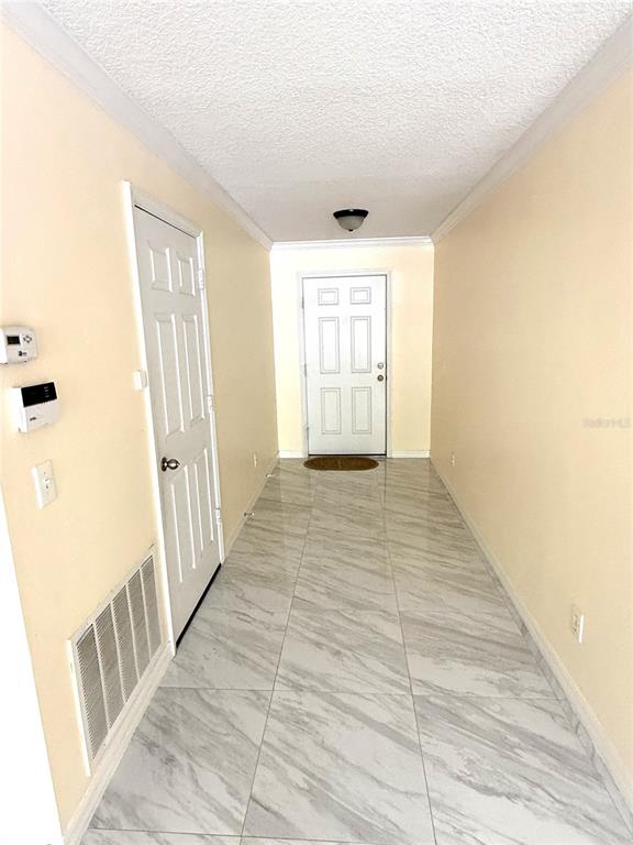 A hallway features light-colored walls, a white door, and large, marble-patterned floor tiles — 344 SKY VALLEY STREET, CLERMONT, FL