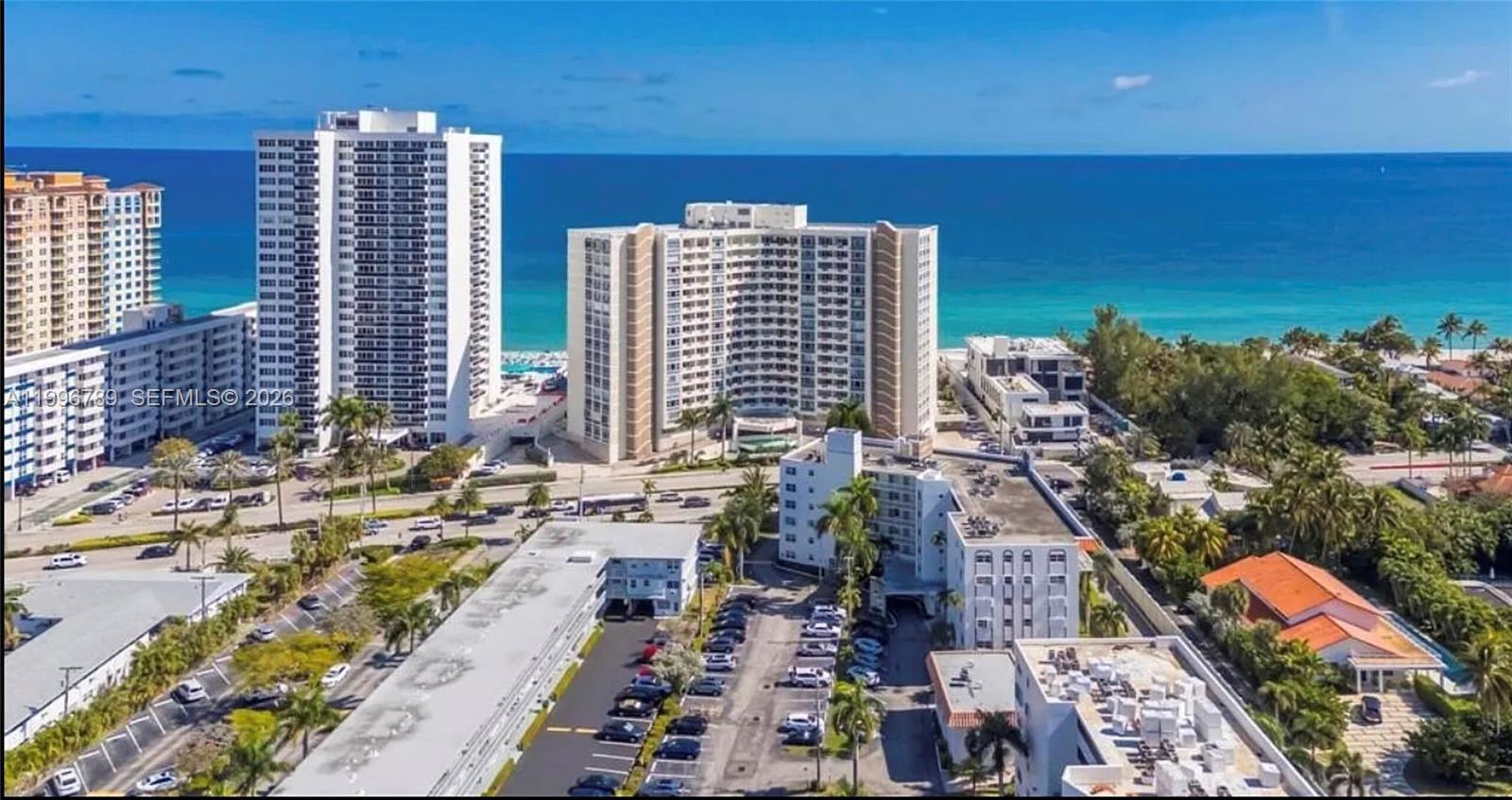 An aerial view shows multiple high-rise apartment buildings located along a sandy beach and ocean — 3181 S Ocean Dr, Hallandale Beach FL 33009, HALLANDALE BEACH, FL