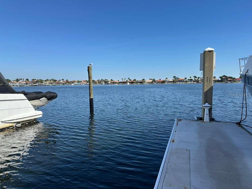 A view from a dock looking across a canal toward houses on the opposite shore — 102 RIVIERA DUNES WAY UNIT C29, PALMETTO, FL