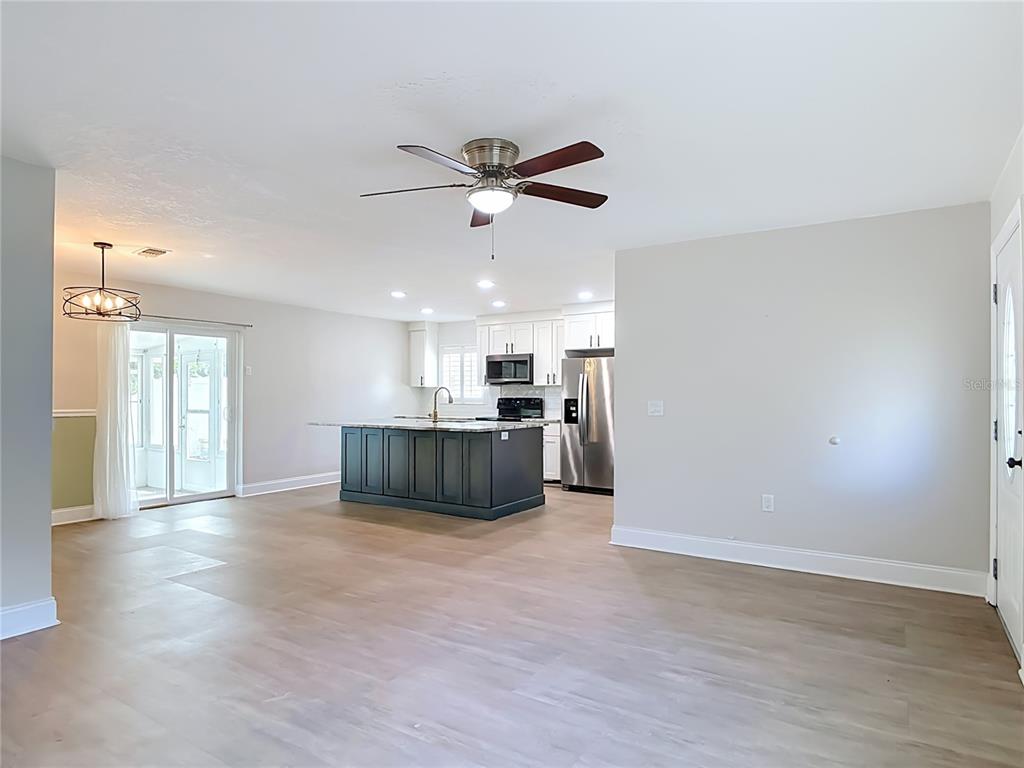 An empty living room features light wood-look flooring, white walls, a ceiling fan, and plantation shutters — 108 ORANGE AVENUE, EDGEWATER, FL