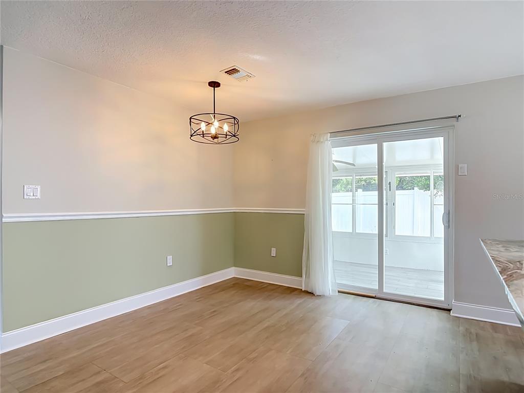 A living room features light gray walls, wood-look flooring, a ceiling fan, and a dining chandelier — 108 ORANGE AVENUE, EDGEWATER, FL