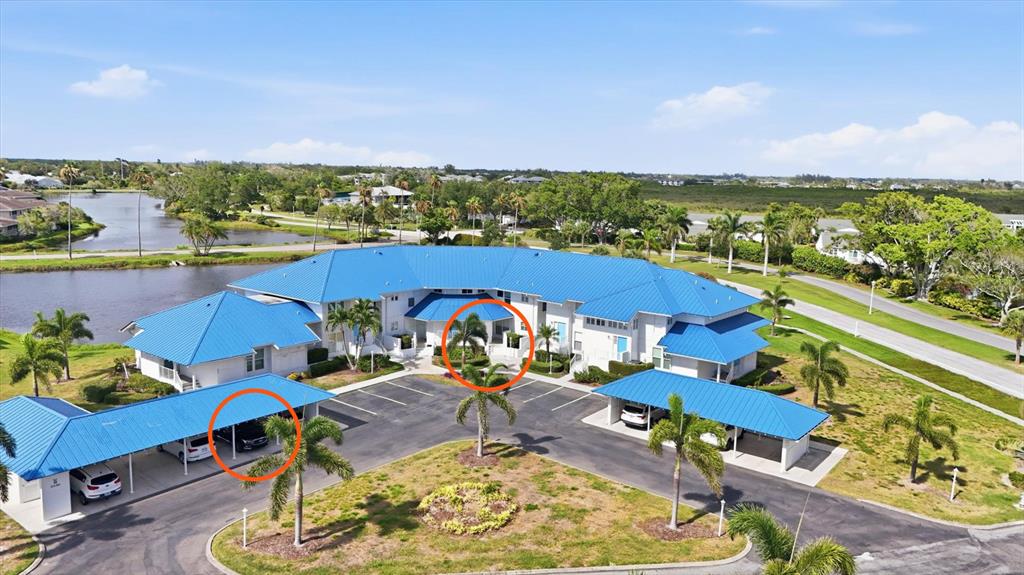 An aerial view shows a residential community with blue-roofed buildings surrounded by water and vegetation — 879 AUDUBON DRIVE UNIT 879, BRADENTON, FL
