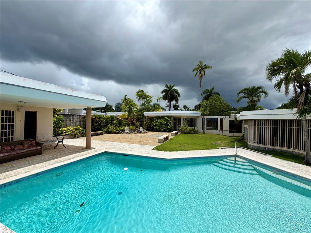 A swimming pool sits in the foreground of a patio area with surrounding residential buildings — 1917 ORQUIDEA, SAN JUAN, PR