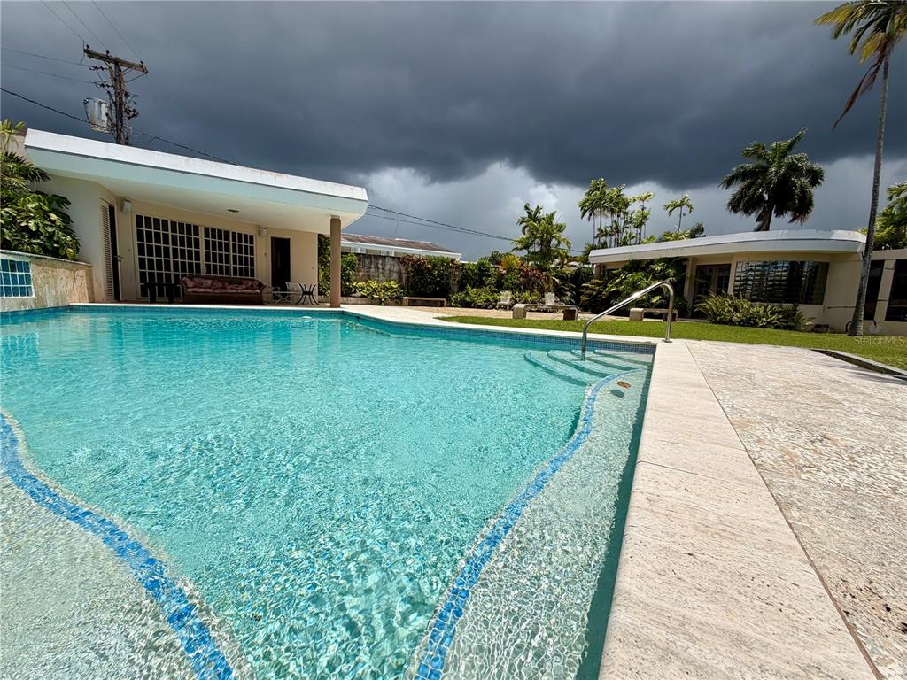 A swimming pool with a metal handrail sits in front of two modern white buildings — 1917 ORQUIDEA, SAN JUAN, PR