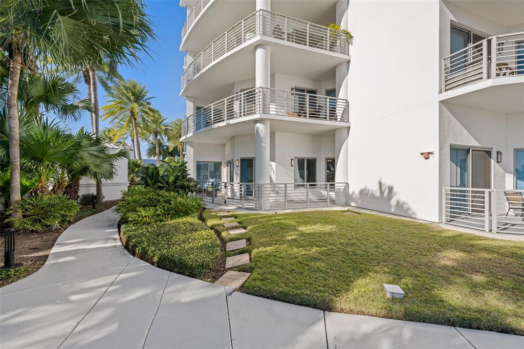 A multi-story white building features balconies, a ground-level patio, and a landscaped lawn — 1209 E CUMBERLAND AVENUE UNIT 501, TAMPA, FL