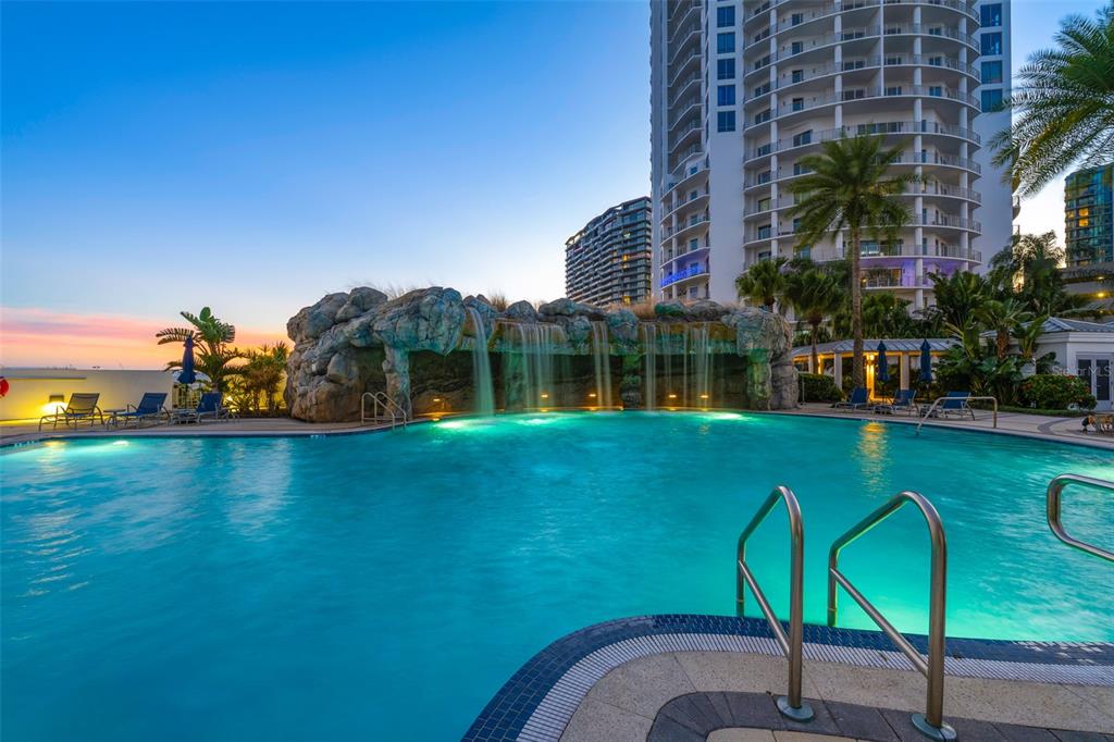 A swimming pool with a rock waterfall feature sits in front of a high-rise building — 1209 E CUMBERLAND AVENUE UNIT 501, TAMPA, FL