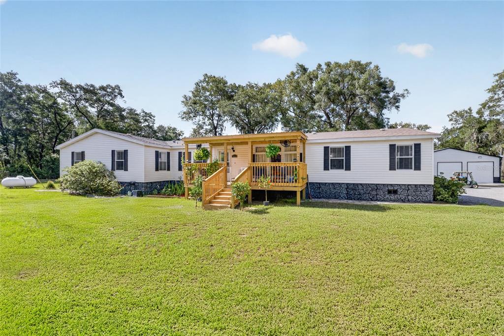 A single-story manufactured home with a wooden front deck sits on a grassy lot — 15680 SE 171ST LANE, WEIRSDALE, FL