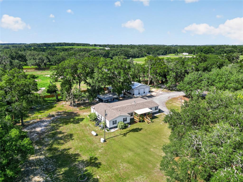 An aerial view shows a single-story house and a detached garage on a grassy lot — 15680 SE 171ST LANE, WEIRSDALE, FL