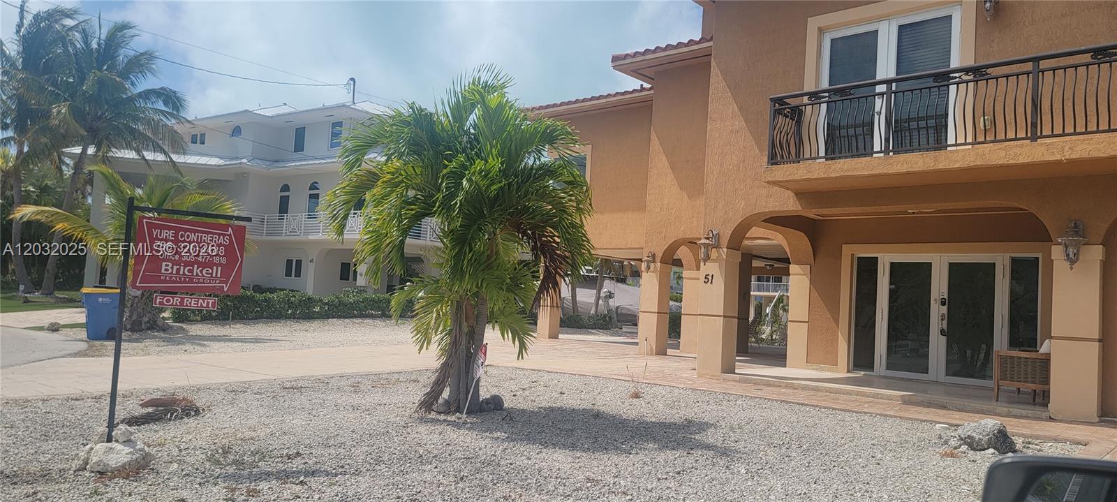 A tan two-story house with a gravel driveway and a for rent sign — 51 W Plaza Del Lago, Islamorada FL 33036, ISLAMORADA, FL