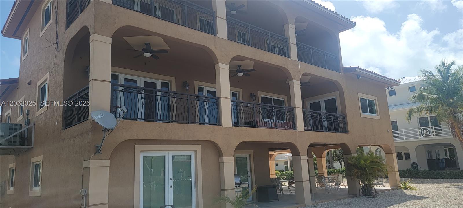 The exterior of a multi-story tan building features arched balconies with black metal railings — 51 W Plaza Del Lago, Islamorada FL 33036, ISLAMORADA, FL