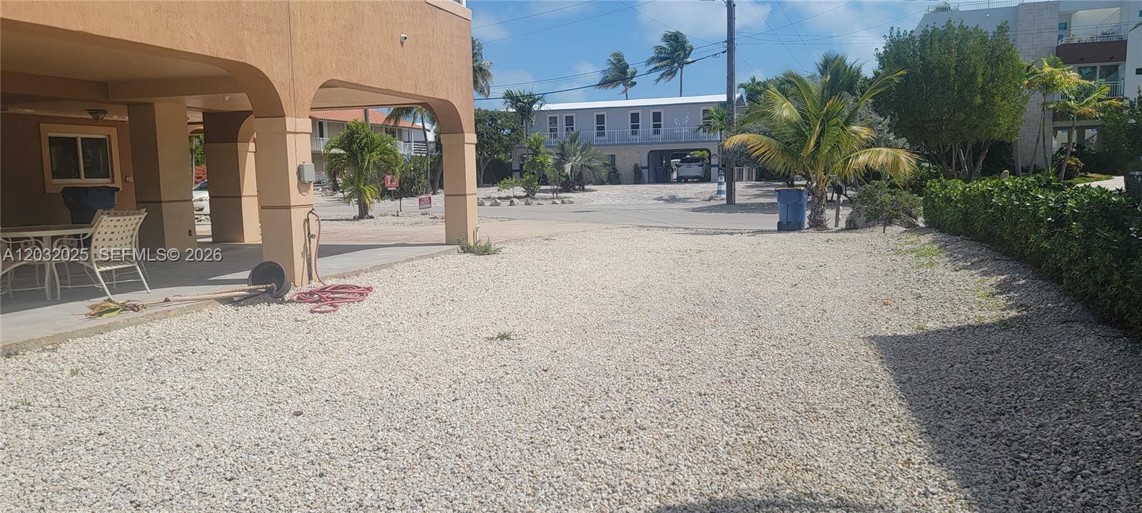 A gravel yard sits in front of a house with a covered patio area — 51 W Plaza Del Lago, Islamorada FL 33036, ISLAMORADA, FL