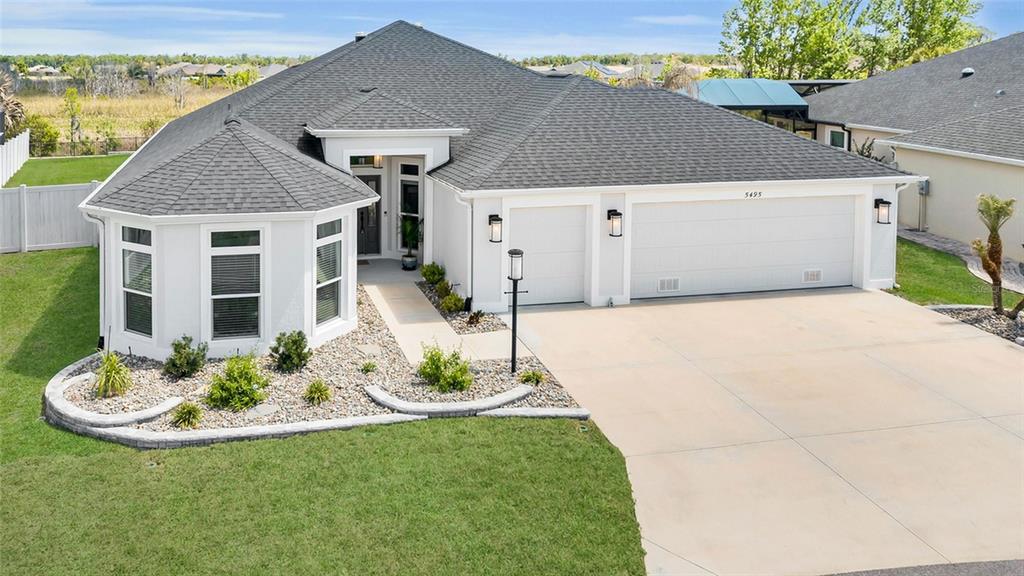 A single-story house with a gray roof, white stucco exterior, and a three-car garage — 5495 HAWKINS DRIVE, THE VILLAGES, FL