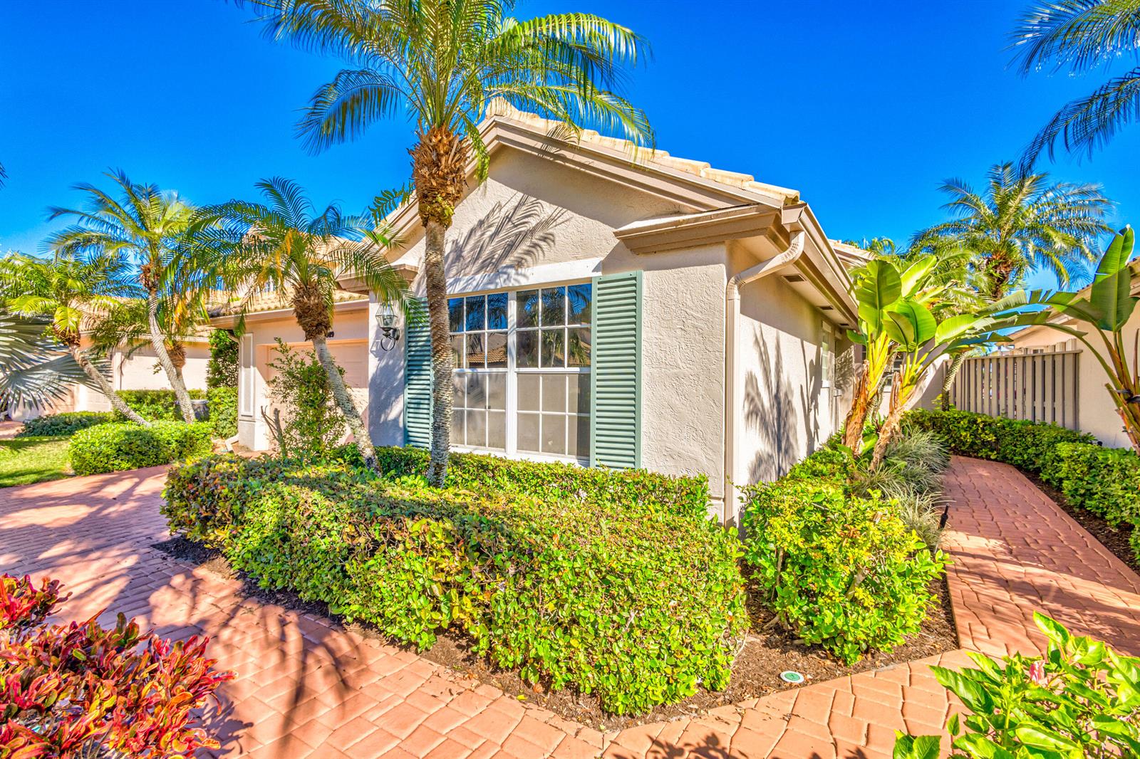 A single-story house with a beige stucco exterior, green shutters, and a brick paver walkway — 919 Augusta Pointe Drive, Palm Beach Gardens FL 33418, PALM BEACH GARDENS, FL