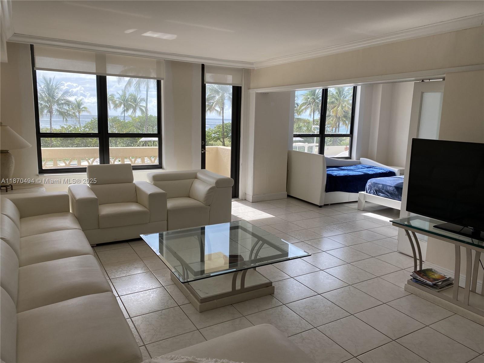 A living room with white leather furniture, a glass coffee table, and ocean views — 10185 Collins Ave # 319, Bal Harbour FL 33154, BAL HARBOUR, FL