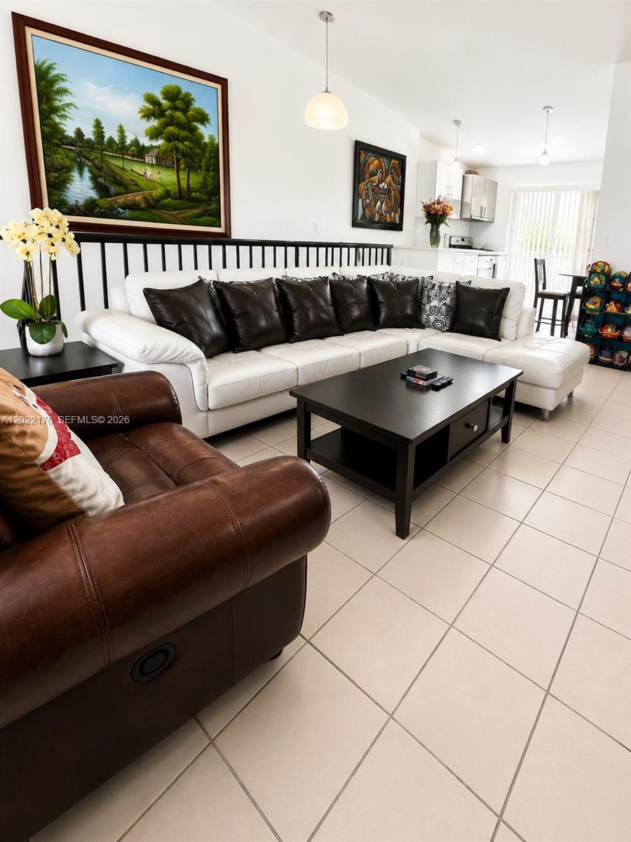 A living room features a white sectional sofa, a brown leather armchair, and tile flooring — 7603 W 29th Ln # 55, Hialeah FL 33018, HIALEAH, FL