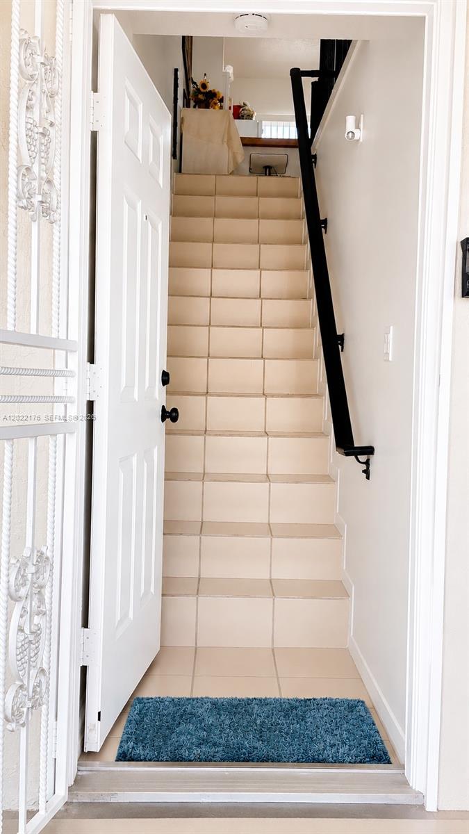 A white door opens to a tiled staircase with a black handrail — 7603 W 29th Ln # 55, Hialeah FL 33018, HIALEAH, FL