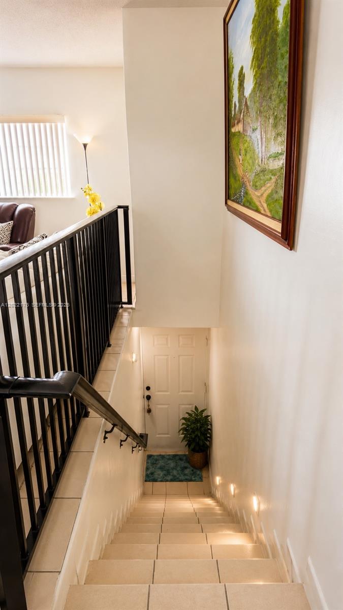 A tiled staircase with a black metal railing leads down to a white door — 7603 W 29th Ln # 55, Hialeah FL 33018, HIALEAH, FL