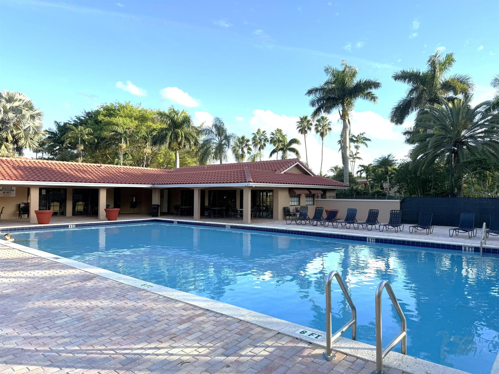A rectangular swimming pool with a brick deck and a covered patio area with palm trees — 8255 Severn Drive # D, Boca Raton FL 33433, BOCA RATON, FL