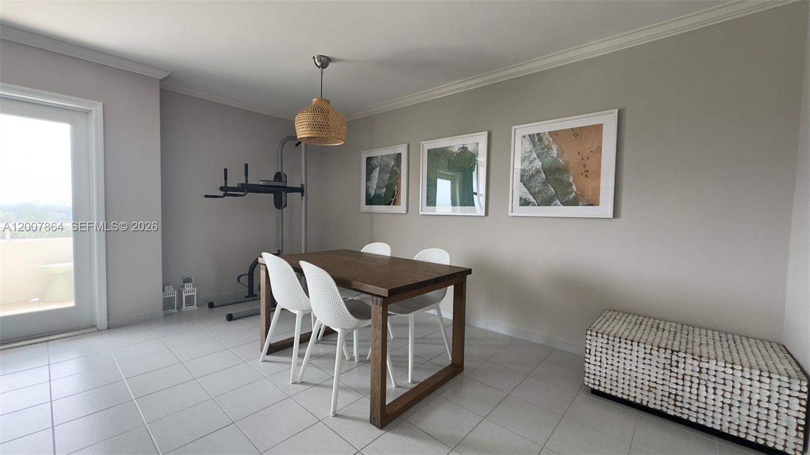 A dining area features a wooden table, white chairs, wall art, and a fitness station — 9225 Collins Ave # 812, Surfside FL 33154, SURFSIDE, FL