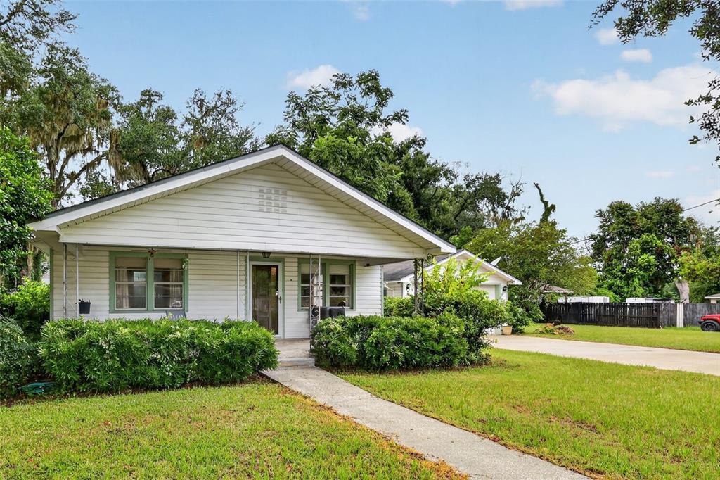 A white single-story house with a red brick chimney and an attached two-car garage — 605 STANLEY AVENUE, WILDWOOD, FL