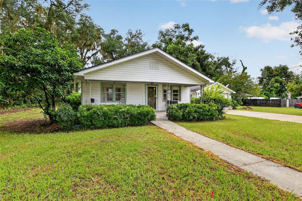 A living room with wood-look flooring, a brick fireplace, two brown armchairs, and a dining area — 605 STANLEY AVENUE, WILDWOOD, FL