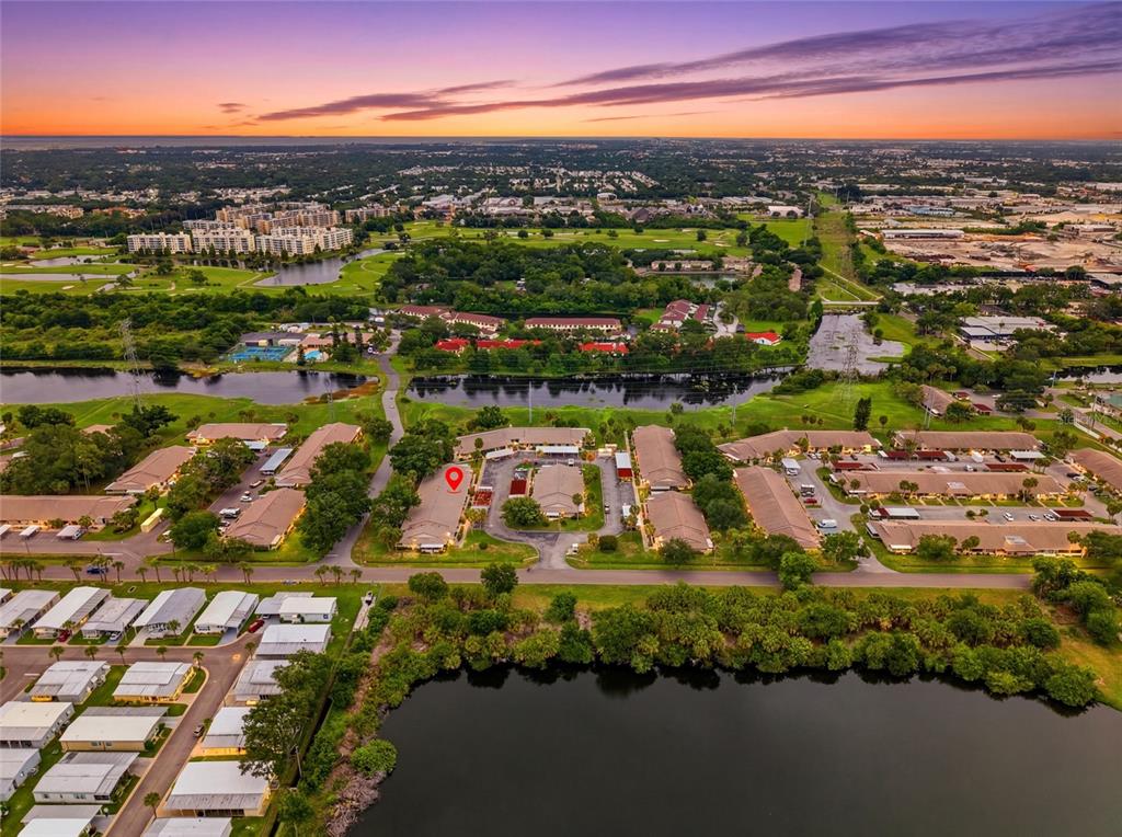 An aerial view shows a residential complex with multiple buildings, parking areas, and a lake — 1208 14TH CIRCLE SE, LARGO, FL