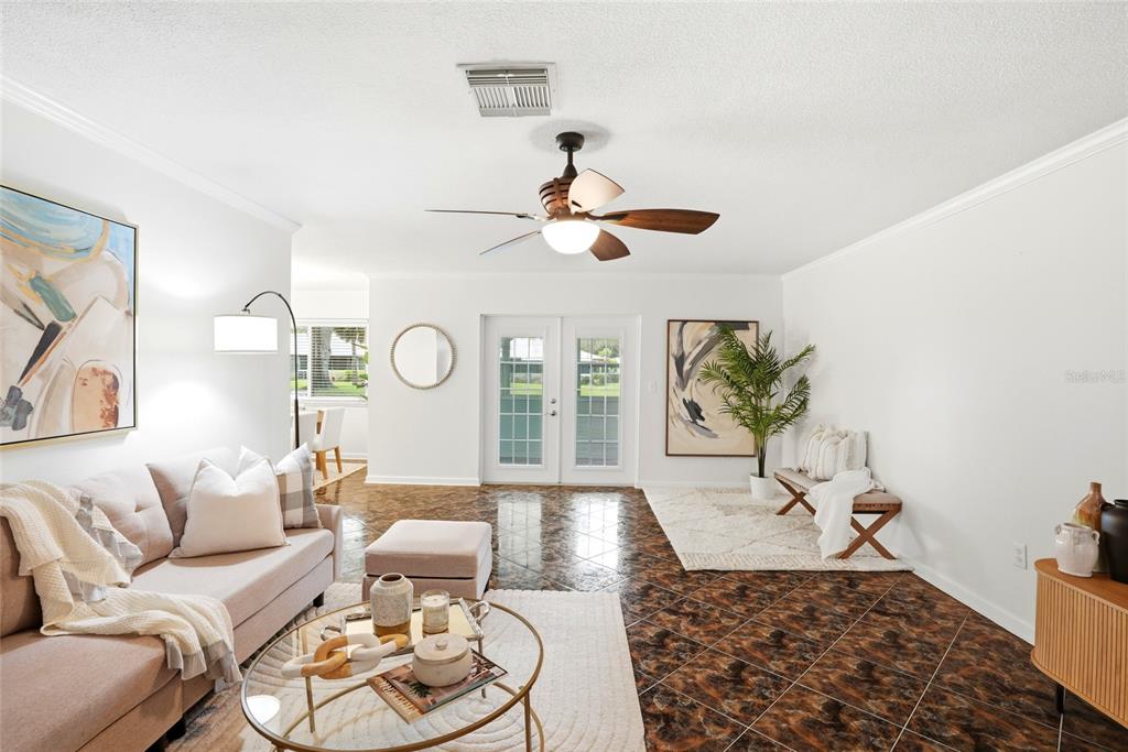 A living room features a beige sofa, glass coffee table, and dark patterned tile flooring — 1208 14TH CIRCLE SE, LARGO, FL