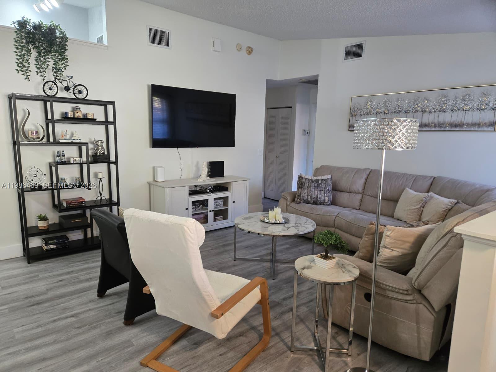 A living room features a sectional sofa, a television, a bookshelf, and marble-topped tables — 3815 Coco Loba Ln, Boynton Beach FL 33436, BOYNTON BEACH, FL