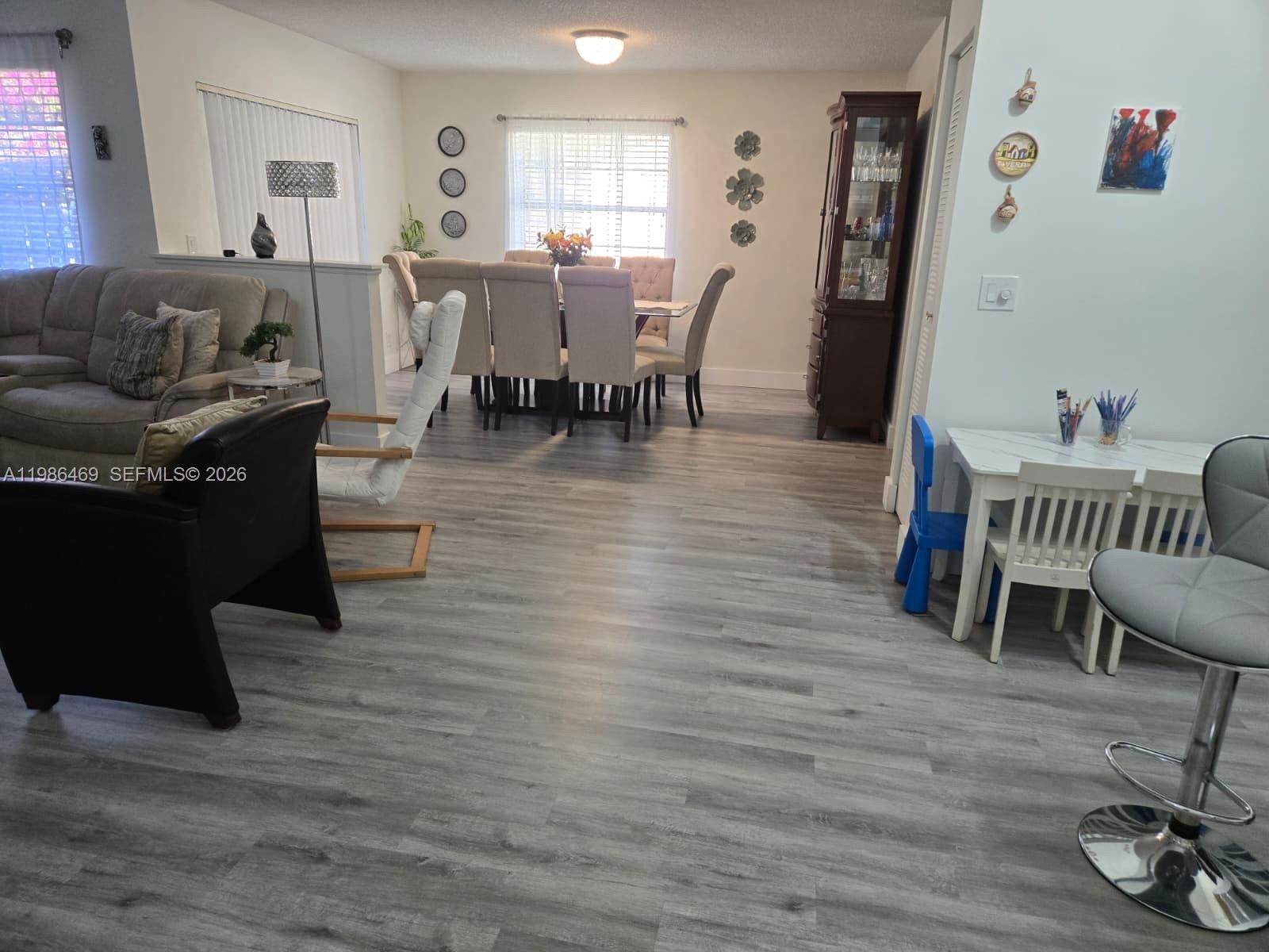 An open-concept living and dining area features light wood-look flooring and neutral-toned furniture — 3815 Coco Loba Ln, Boynton Beach FL 33436, BOYNTON BEACH, FL