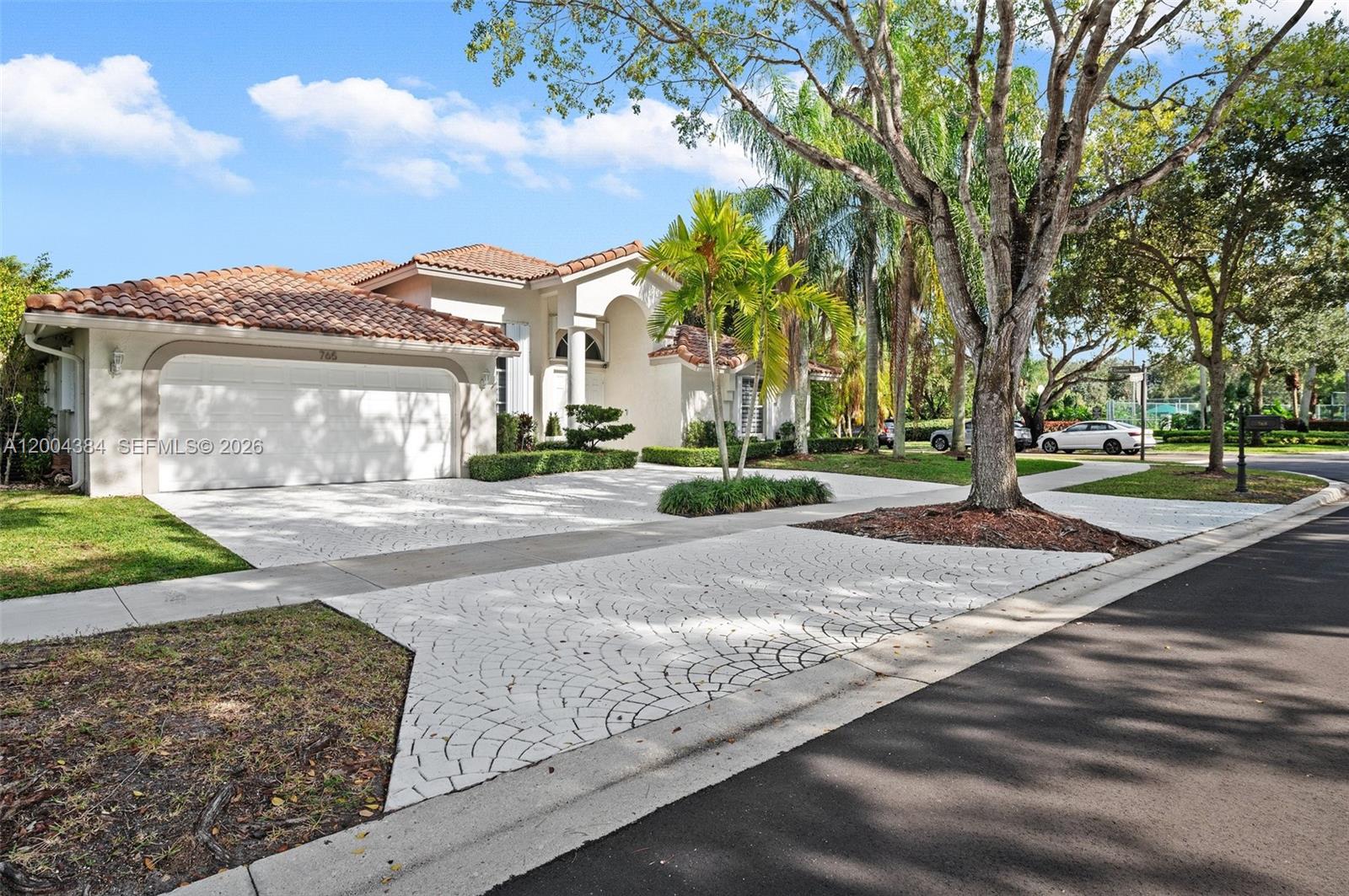 A single-story house with a white garage, tiled roof, and a patterned concrete driveway — 765 Bayside Ln, Weston FL 33326, WESTON, FL