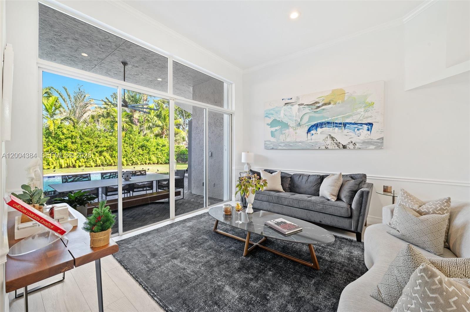 A living room features a dark gray sofa, marble coffee table, and large sliding glass doors — 765 Bayside Ln, Weston FL 33326, WESTON, FL