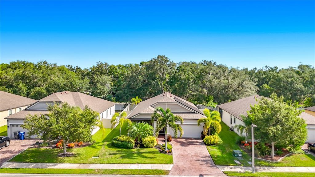 An aerial view shows three suburban houses with paved driveways and green lawns under a blue sky — 3902 76TH STREET E, PALMETTO, FL