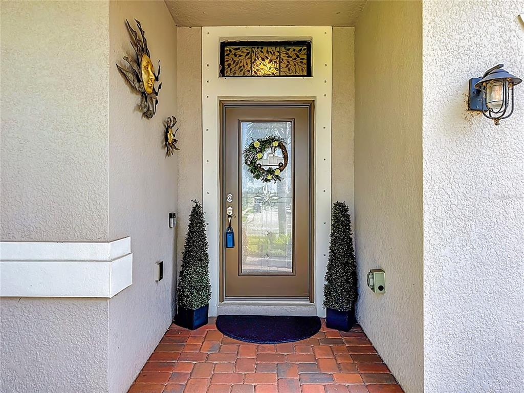 A front entryway features a brown door with a glass insert, transom window, and topiaries — 3902 76TH STREET E, PALMETTO, FL
